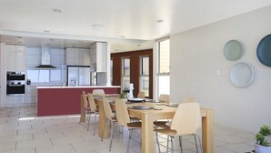 Une cuisine moderne avec des meubles blancs, un îlot central et un coin repas comprenant une table et des chaises en bois.