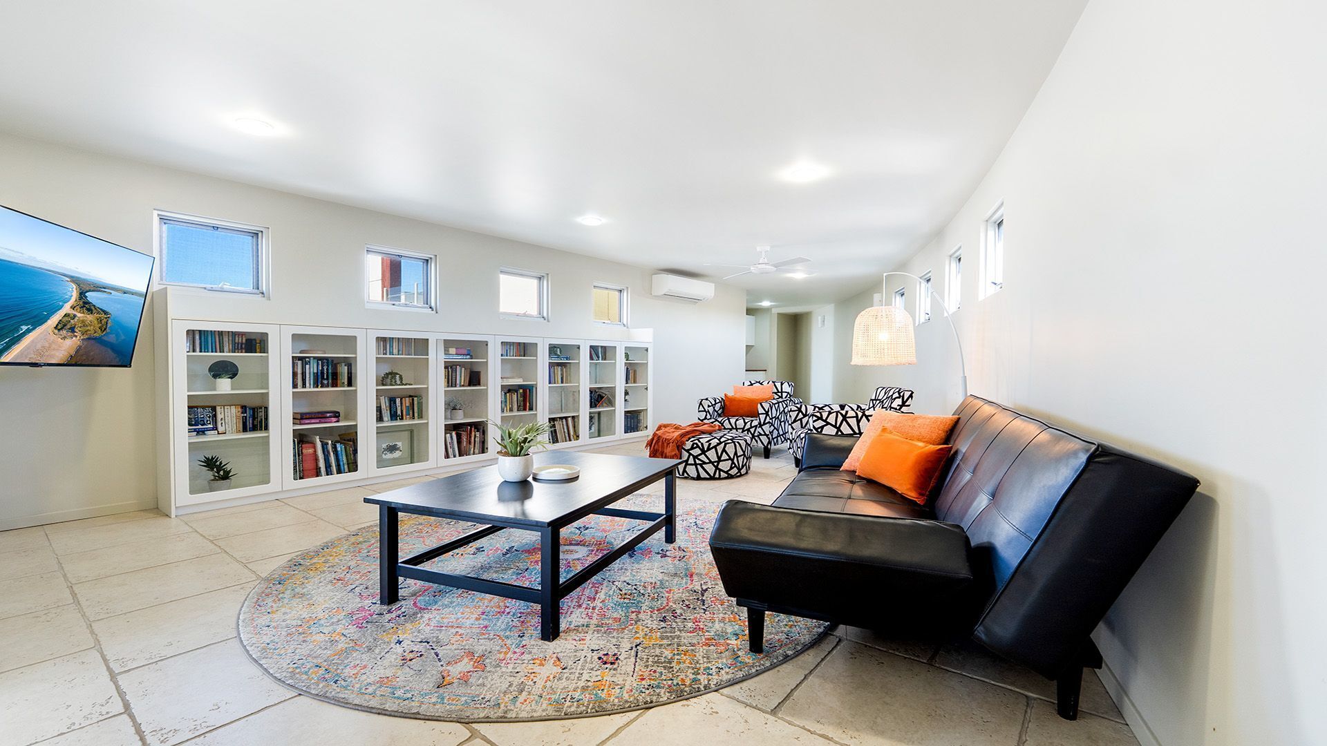 Ein modernes Wohnzimmer mit einem schwarzen Ledersofa, einem Couchtisch und einem Bücherregal voller Bücher.