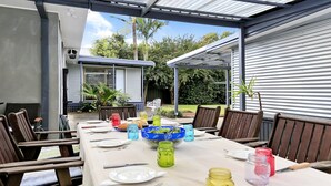 An outdoor dining area with a long table, chairs, and a covered patio. - Gone Fishing! - ideal for larger families and groups with pets (Culburra Beach)