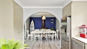A modern kitchen with a dining area, a surfboard decoration, and a popcorn machine. - Gone Fishing! - ideal for larger families and groups with pets (Culburra Beach)