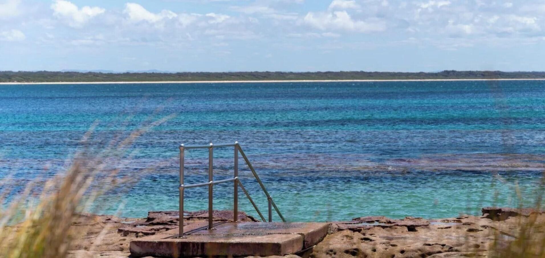 A clear view of a beach with a metal structure in the foreground and a sandy beach extending to the horizon.