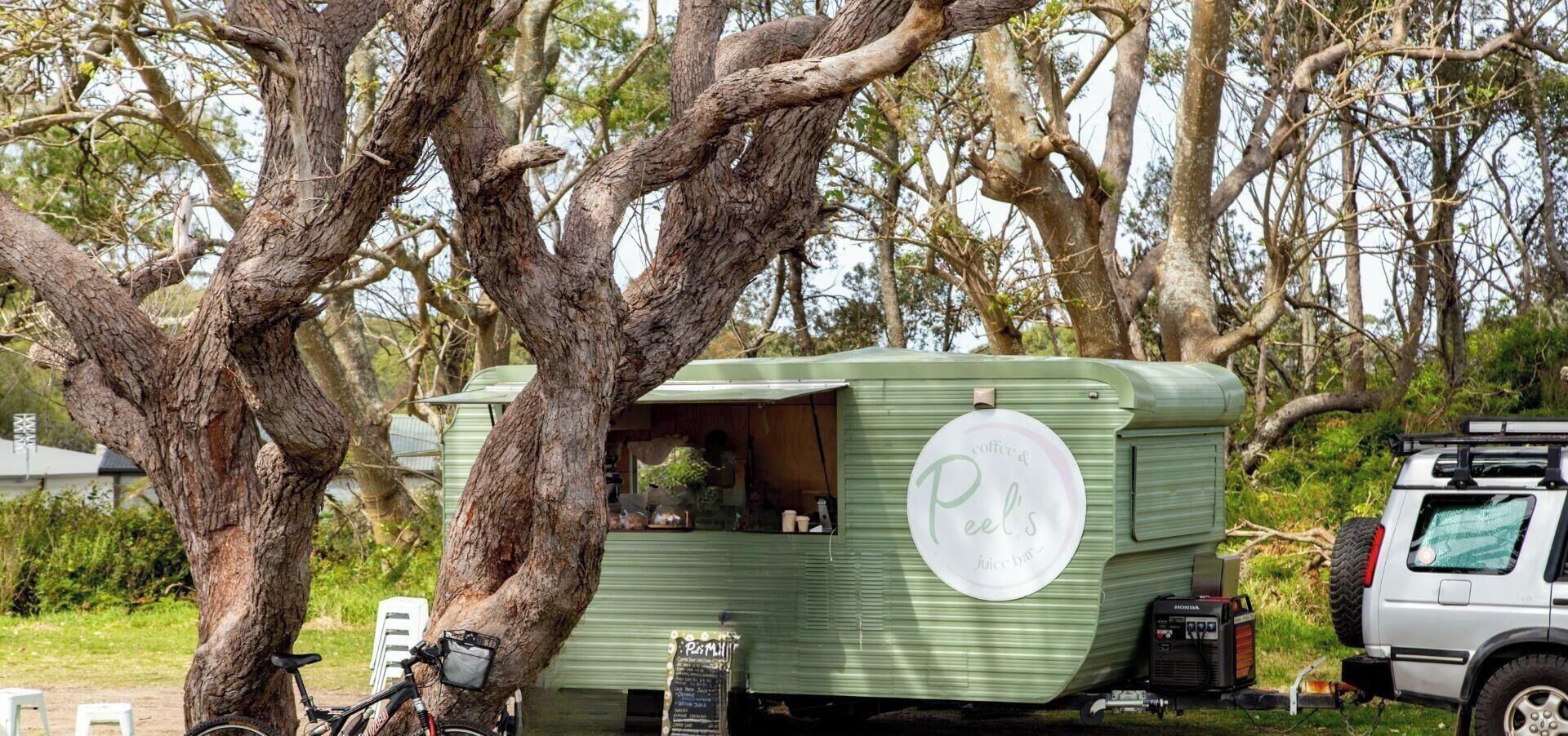 A green mobile home with a sign reading 'Peel's Coffee & Juice Bar' and a visible interior.