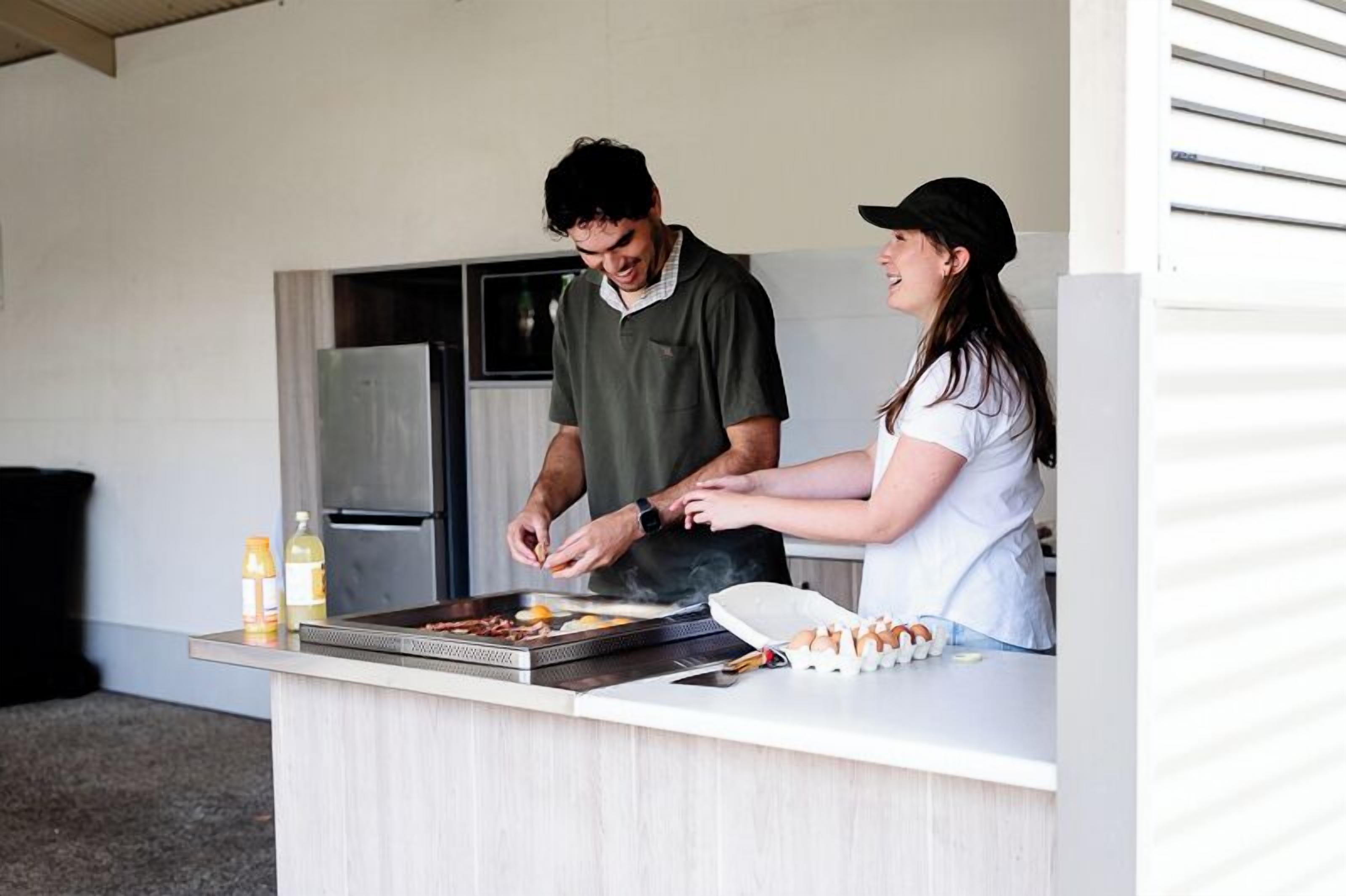 A kitchen with a grill, a refrigerator, and a counter with food items.