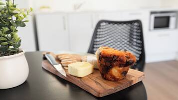 A wooden board with a muffin, a knife, and a butter knife on a table.