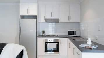 A modern kitchen with white cabinets, stainless steel appliances, and a black countertop.