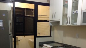 Eine kleine Küche mit Kühlschrank, Herd und Schränken.