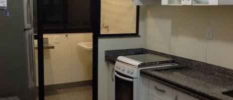 A compact kitchen with a refrigerator, stove, and cabinets.