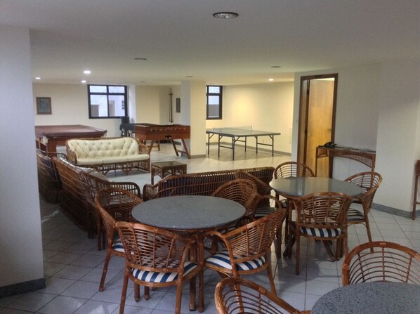 A dining area with wicker furniture, a sofa, and a billiards table.