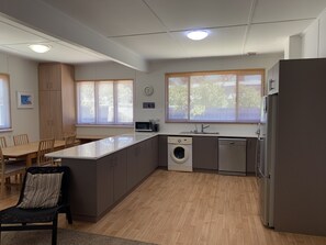 Eine moderne Küche mit Kochinsel, integrierten Geräten und einem Essbereich mit Tisch und Stühlen.