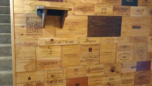 Seinä, jossa on puupaneeleita ja niissä esillä erilaisia viinipullojen etikettejä.