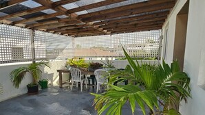 Un patio couvert doté d’un plafond en bois, de murs en treillis blanc et d’une table avec des chaises.