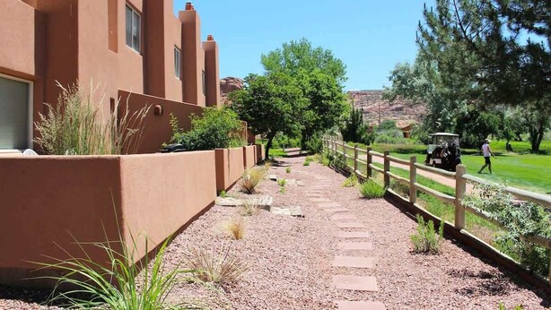 A pathway leading to a building with a flat roof and a wooden fence. - Adobe Dreams - 3292, Private hot tub (Moab)
