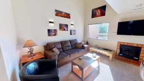 A living room with a sofa, coffee table, lamp, and fireplace. - Adobe Dreams - 3292, Private hot tub (Moab)