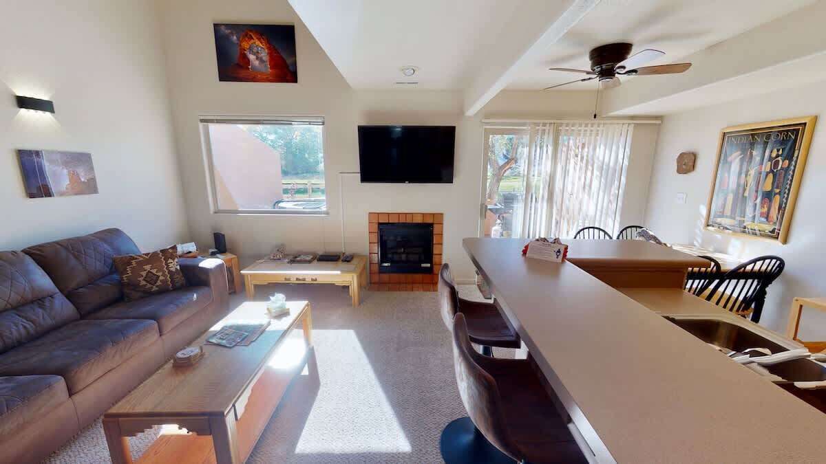 Een woonkamer met een bank, salontafel, open haard, televisie en een eethoek met stoelen.