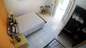 Una camera da letto con un letto, una sedia, un tavolino, un armadio e una finestra con tende.