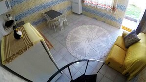 Una cucina con tavolo e sedie, un divano giallo e un pavimento decorato.