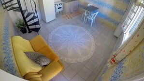 Un ambiente compatto con angolo cottura, zona pranzo e una scala.