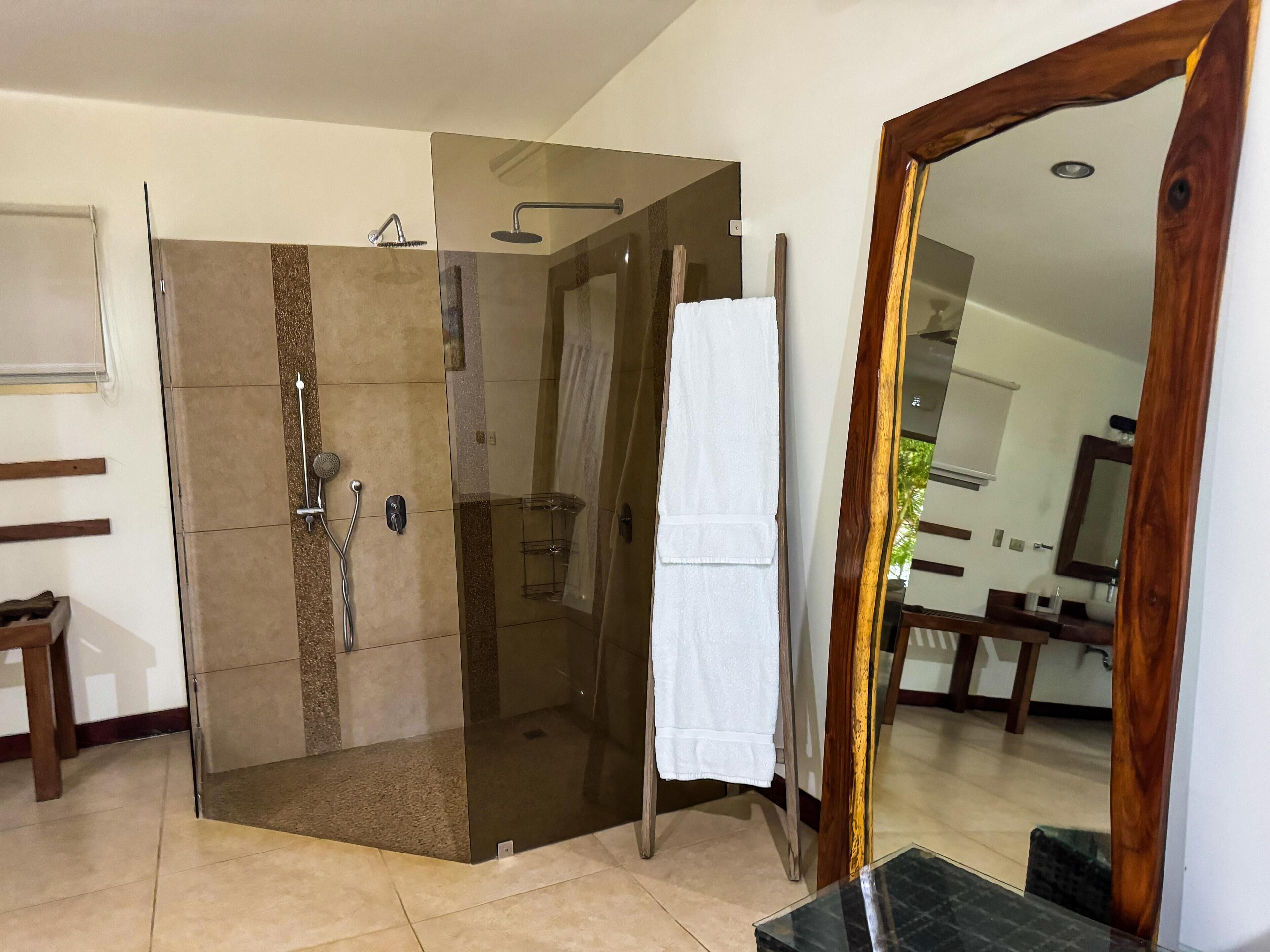 A modern bathroom with a glass-enclosed shower, a wooden vanity, and a large mirror.