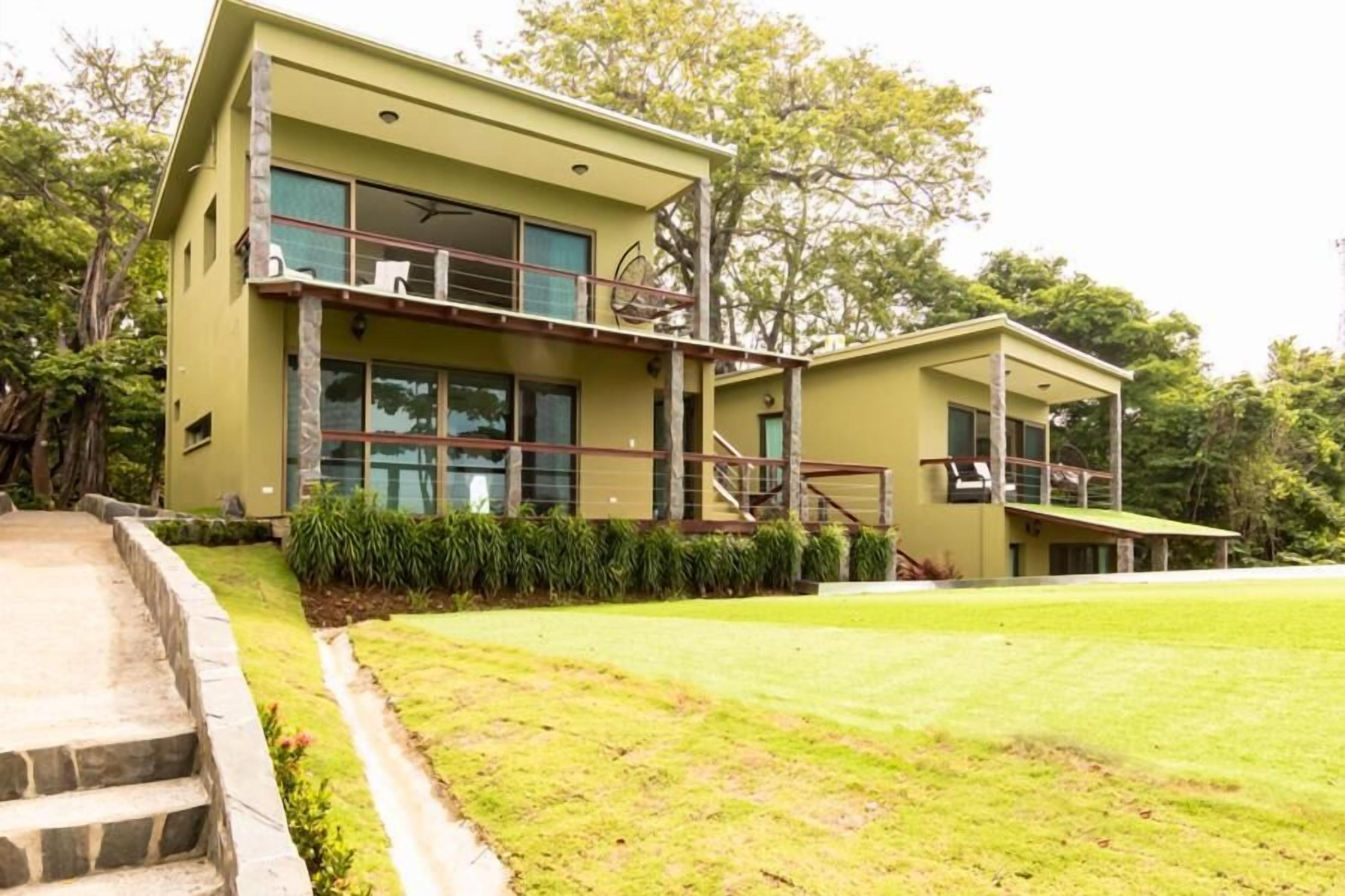 A two-story building with a balcony, a staircase, and a well-maintained lawn.