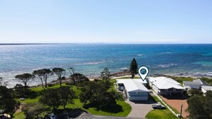 Une propriété située sur la côte, offrant une vue sur la mer, avec une piscine et une grande maison dotée d’un garage.