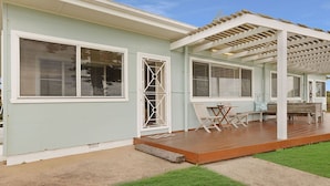 Une maison bleu clair avec un porche abrité, de grandes fenêtres et une terrasse en bois.