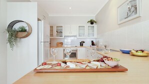 Une cuisine moderne avec des meubles blancs, un plan de travail en bois et un panier de fruits.