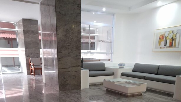 Un amplio salón con piso de mármol pulido, un conjunto de sofás grises y una mesa de centro moderna.
