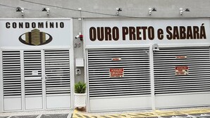 A building with two garage doors labeled "CONDOMÍNIO" and "OURO PRETO e SABARÁ".