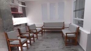 Una habitación con piso de mármol, sillas de madera, un banco y un amplio ventanal.