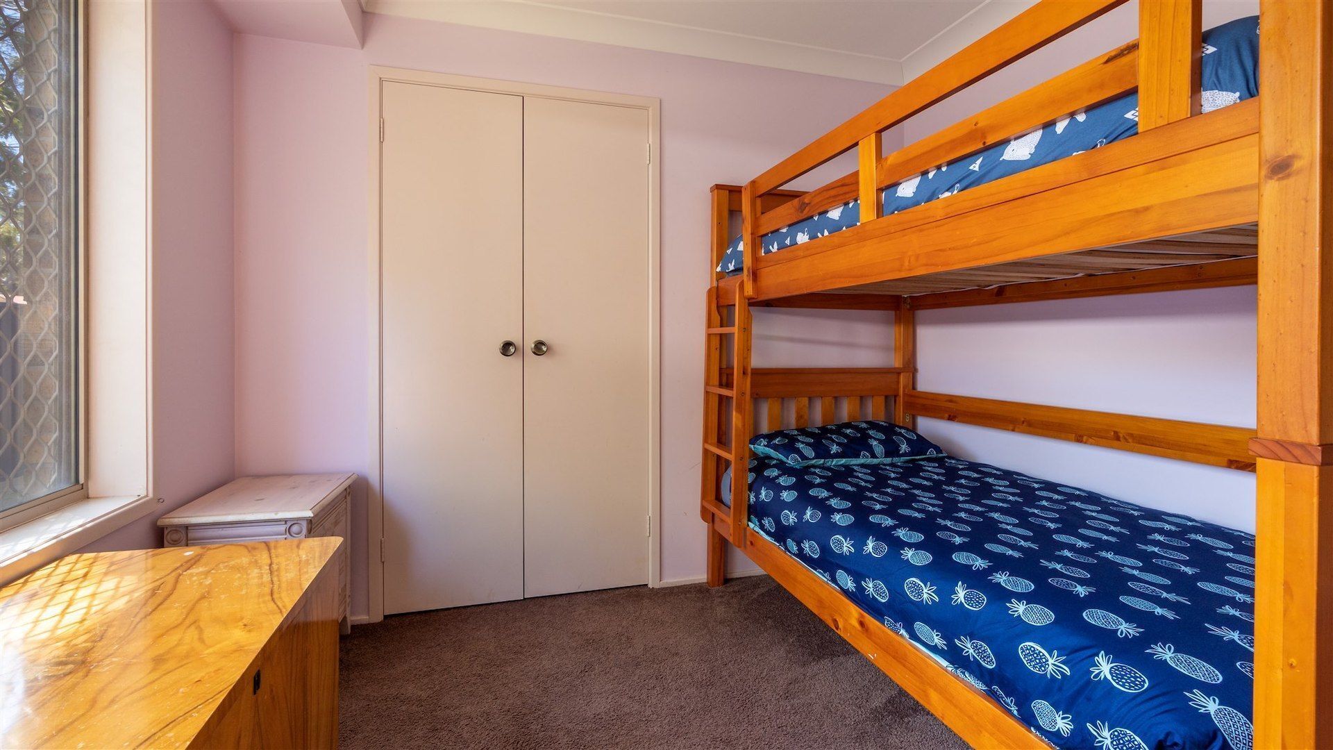 A bunk bed room with a door, a small desk, and a window.