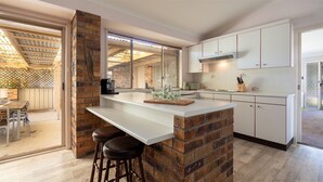 A modern kitchen with a brick accent wall, white cabinetry, and a bar area with stools.