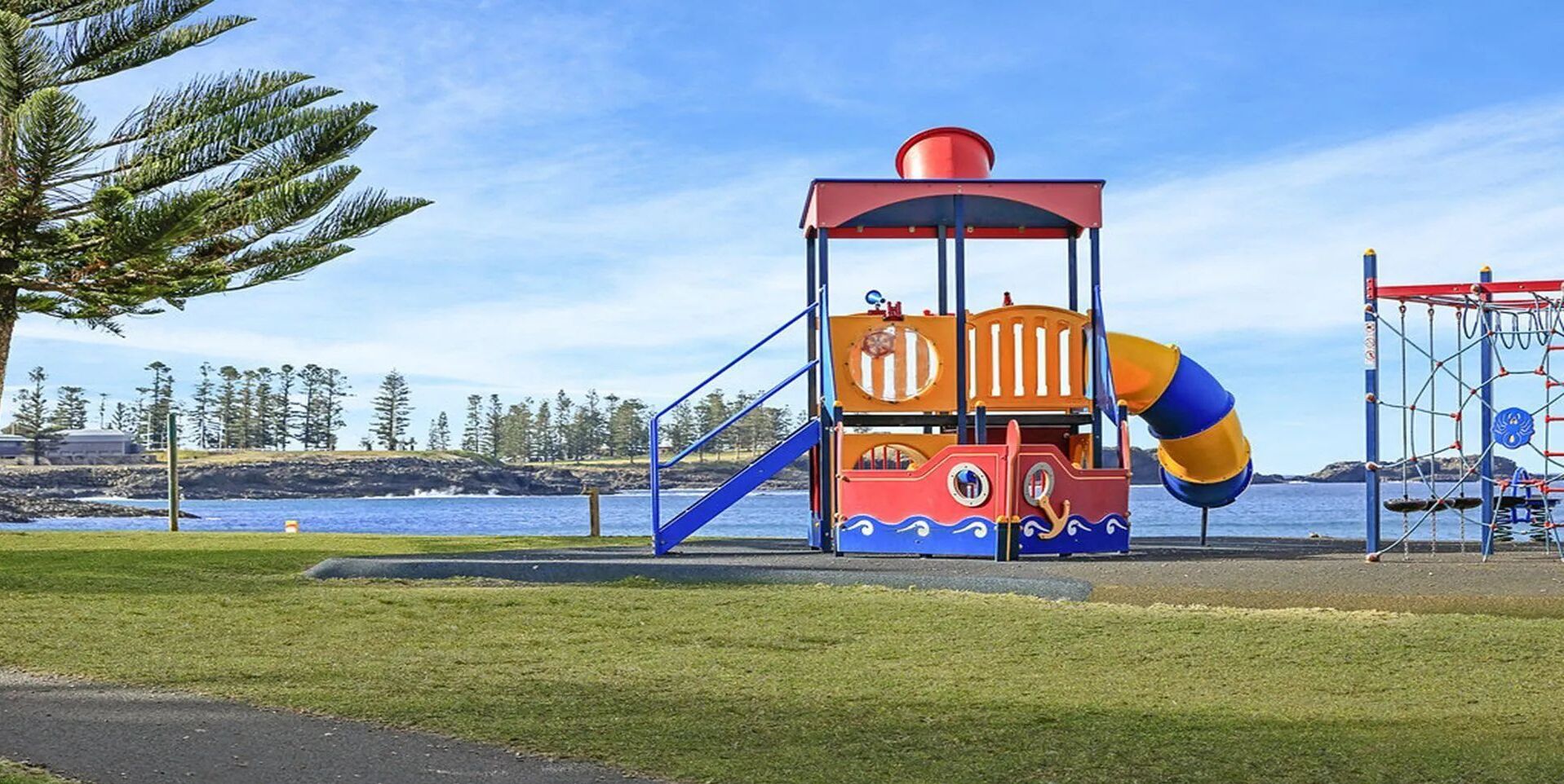 Un parque infantil con un tobogán y estructuras para escalar cerca del agua.