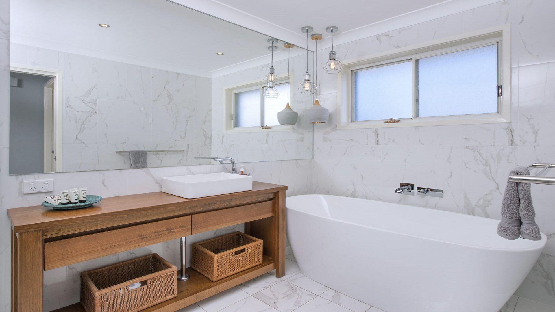 Een moderne badkamer met een vrijstaand bad, een houten wastafelmeubel en een grote spiegel.