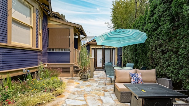 A patio area with stone flooring, outdoor furniture, and a large umbrella.