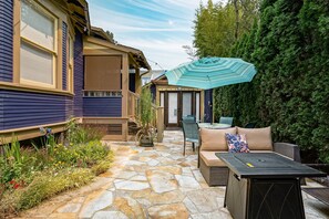 A patio area with stone flooring, outdoor furniture, and a large umbrella. - Patio Suite: sleeps 1 to 2; patio; gas fire pit (Portland)