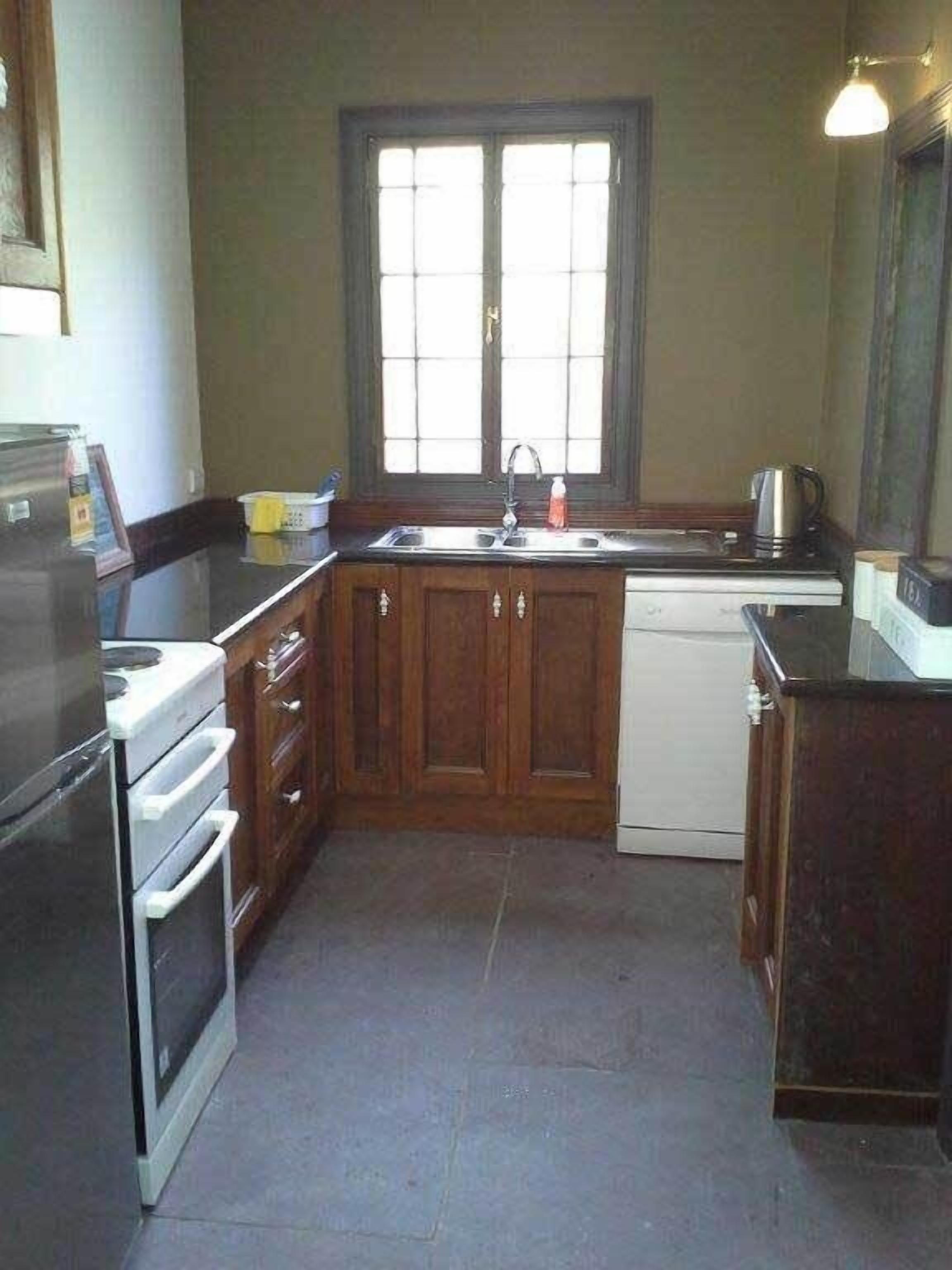 Una cocina con armarios de madera, un lavamanos, una estufa y un lavavajillas.