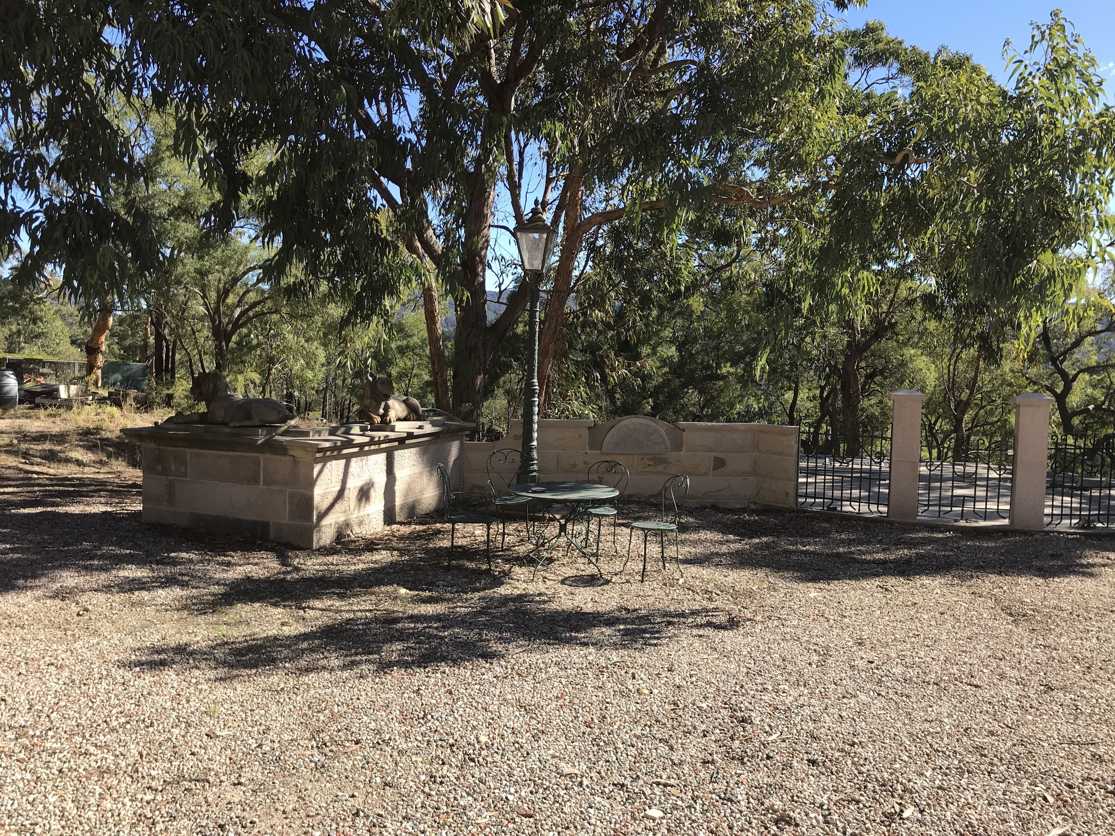 A park area with a stone bench, metal chairs, and a fence.
