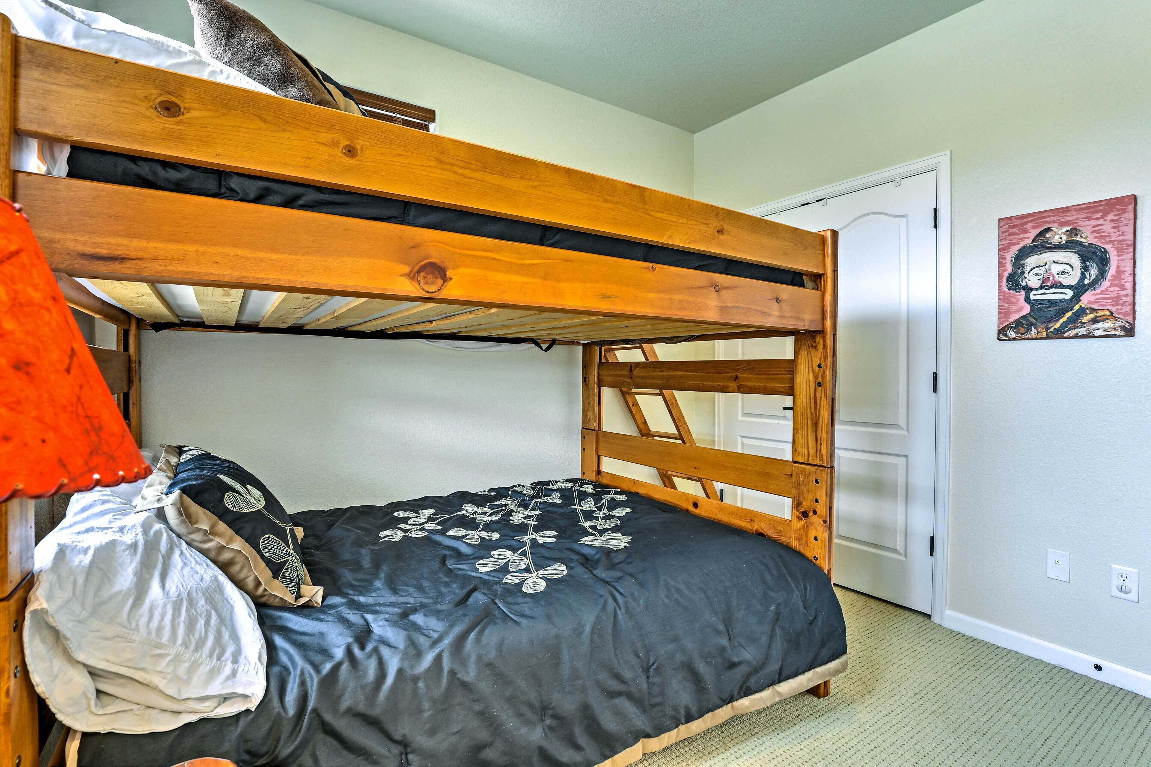 A bunk bed with a wooden frame, a black mattress with leaf patterns, and a white door in the background.