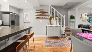 Una cocina moderna con una isla grande, sillas de madera y una escalera que sube a una zona tipo loft.