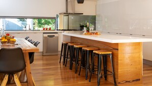 A modern kitchen with a central island, bar stools, and a dining area with chairs.