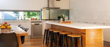 A modern kitchen with a central island, bar stools, and a dining area with chairs.