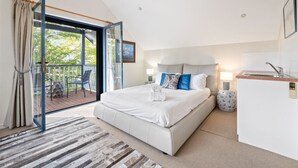 A modern bedroom with a large bed, a small kitchenette, and a balcony with outdoor furniture. - The River House - In the heart of Margaret River - idyllic getaway for families (Margaret River)