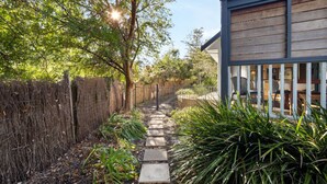 A pathway leading to a building with a wooden exterior and a fenced garden area. - The River House - In the heart of Margaret River - idyllic getaway for families (Margaret River)
