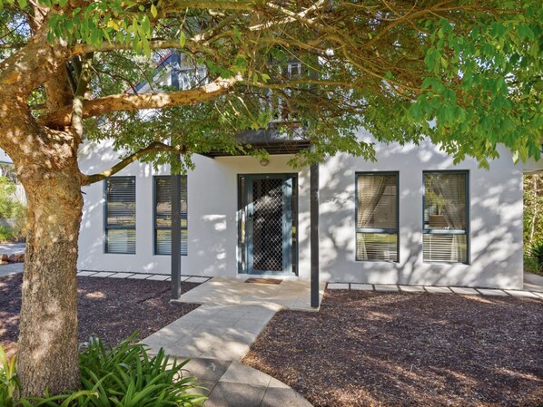 A modern house with a white exterior, a black door, and a small porch area.