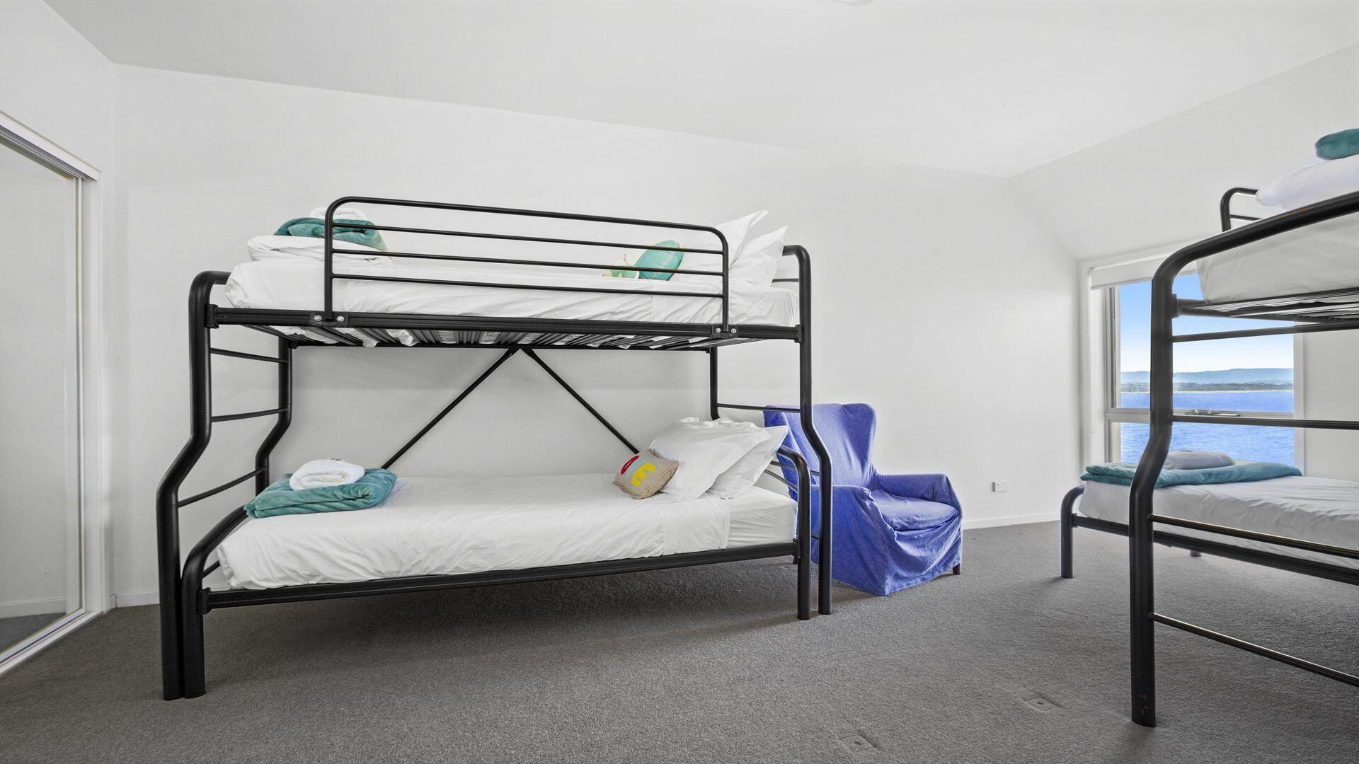 A bunk bed room with a view of the sea through a window.
