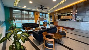A hotel lobby with a reception desk, seating area, ceiling fan, and large windows. - Adya Hotel Chenang (Langkawi)