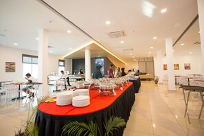 A spacious indoor dining area with a long table covered in a red tablecloth, surrounded by white chairs. - Adya Hotel Chenang (Langkawi)