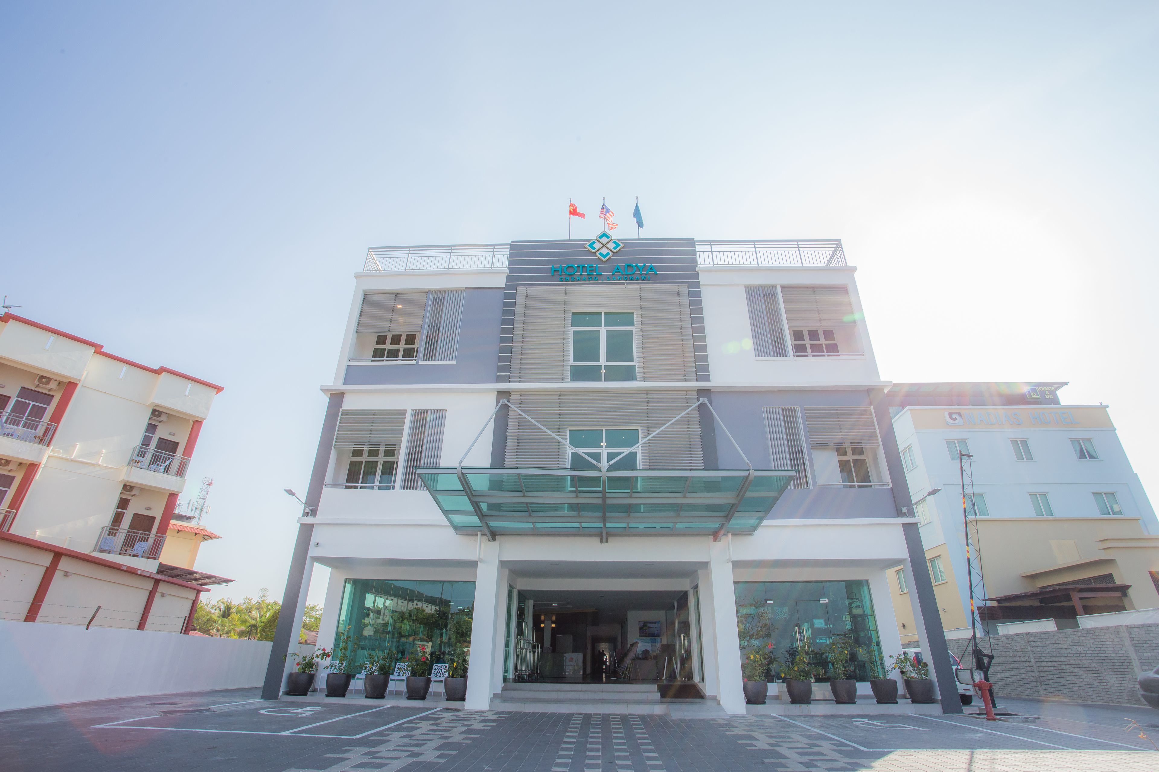 A hotel with a modern design, featuring a glass entrance canopy and multiple flags.
