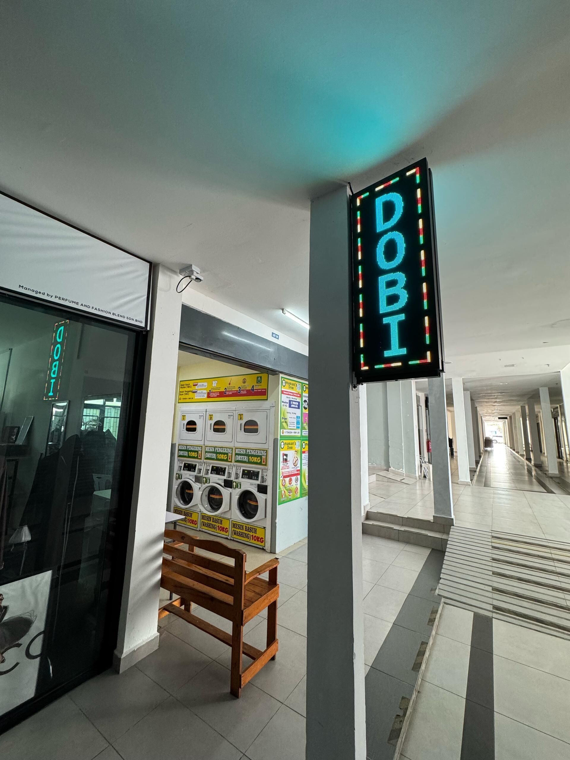 A clean, modern interior with a neon sign reading "DOBI", a washing station, and a wooden bench.