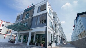 A modern hotel with a glass entrance, outdoor seating, and a covered area. - Adya Hotel Chenang (Langkawi)
